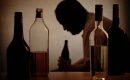 silhouette of a person drinking behind bottles of alcohol