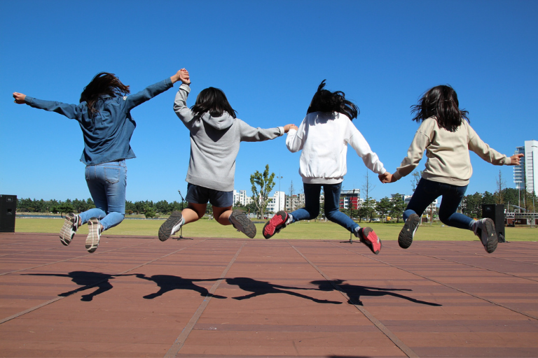girls holding hands and jumping